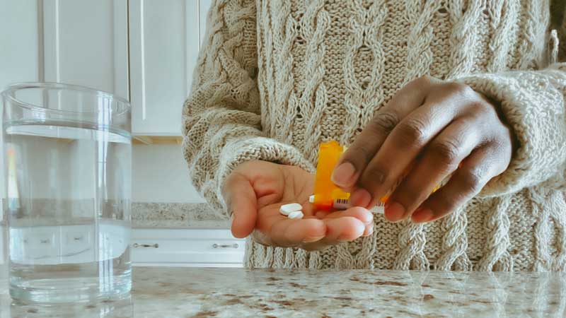 person putting pills in their hand