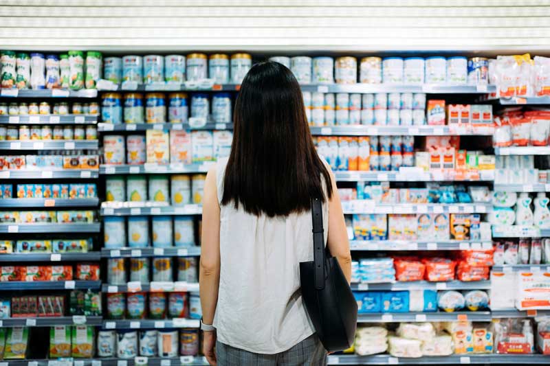 Una mujer mirando yogures en los estantes de la tienda de comestibles