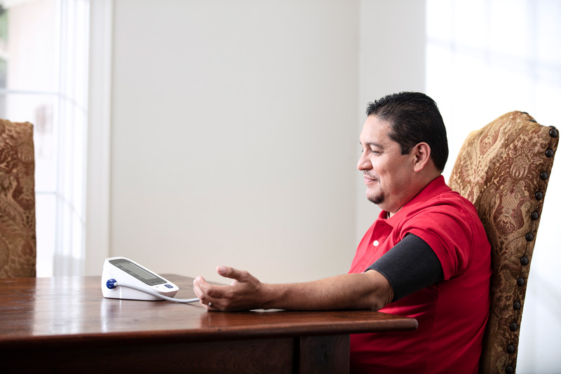 Hombre hispano revisando su presión arterial