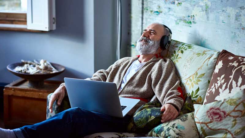 Un hombre mayor que se relaja en el sofá con audífonos