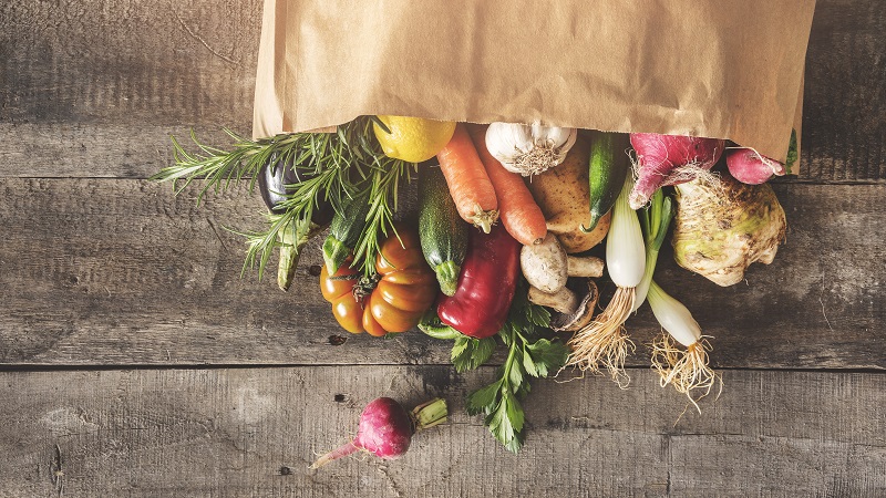 vegetables falling out of brown grocery bag onto table vegetables falling out of brown grocery bag onto table