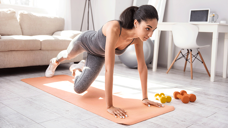 Woman exercising on mat with weights near