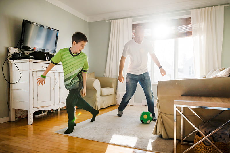 dad and son play indoor soccer at home