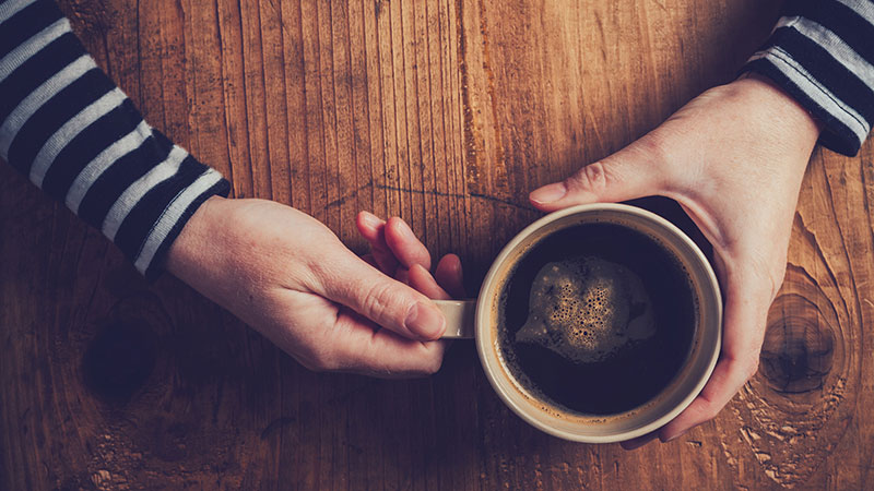 manos sujetando una taza de café