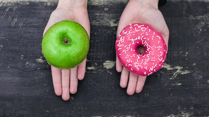 manos que muestran la elección entre una manzana o un donut