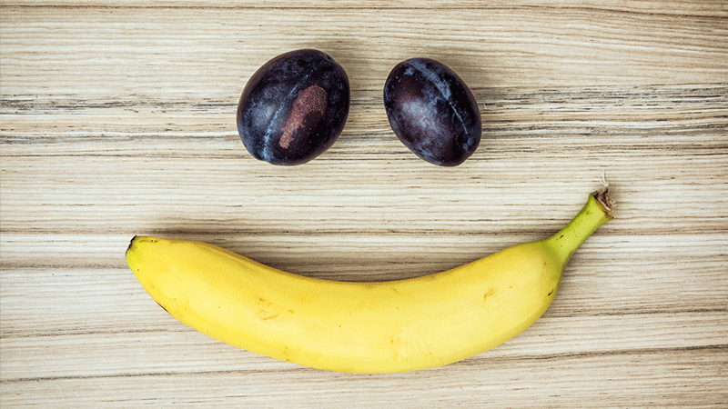 Cara sonriente de plátano y uvas