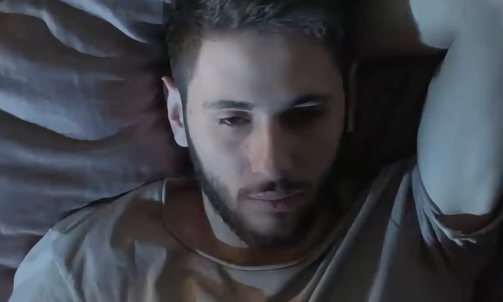 man in bed having hard time getting to sleep