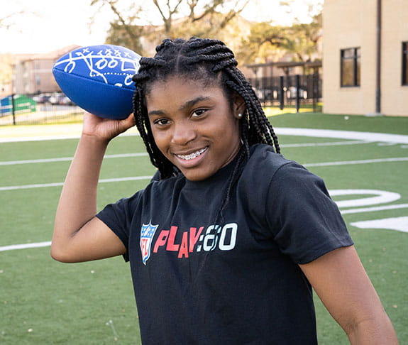 Young teen female smiling while throwing a blue football