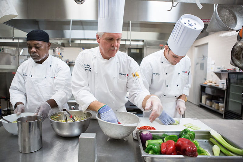 Racially diverse group of chefs prepping food in professional kitchen
