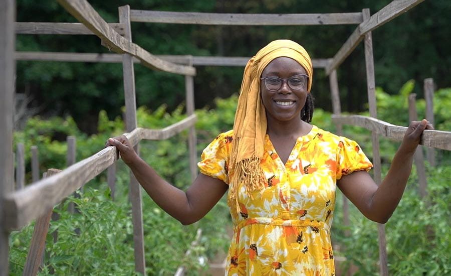 A Black woman smiling in a community garden