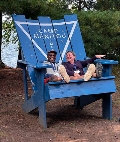 dos personas sentadas en un sillón Adirondack azul gigante al aire libre