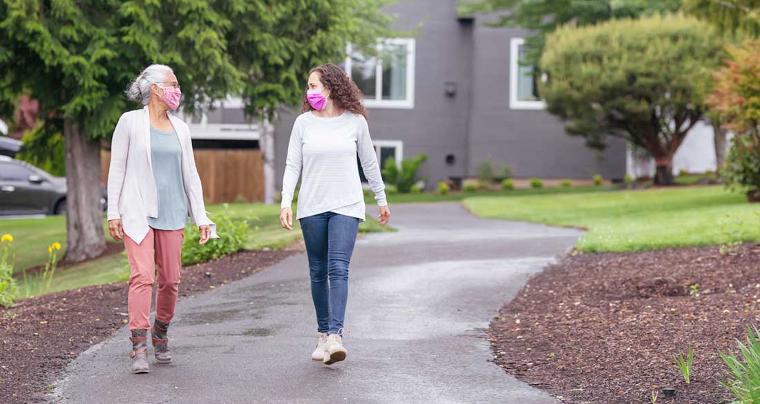 mother and adult daughter walking in neighborhood wearing masks mother and adult daughter walking in neighborhood wearing masks