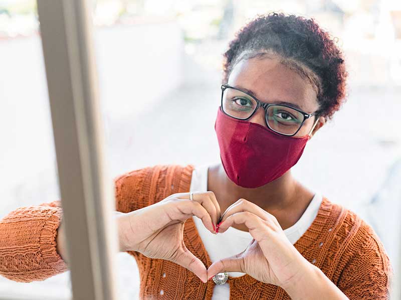 woman wearing mask motioning heart with hands woman wearing mask motioning heart with hands