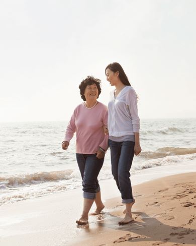 abuela y nieta pasean por la playa dos mujeres, probablemente madre e hija, caminan por la playa