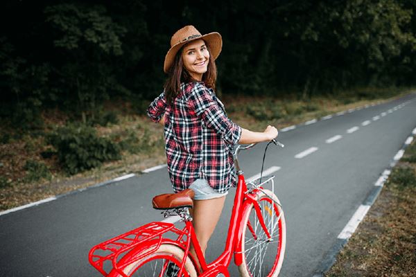 young woman walking red vintage bicycle down a tree-lined street young woman walking red vintage bicycle down a tree-lined street