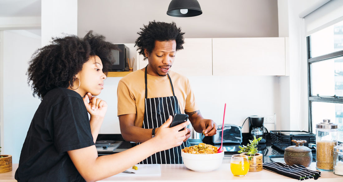 woman shows man how to cook using phone woman shows man how to cook using phone