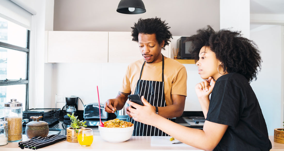 woman shows man how to cook using phone woman shows man how to cook using phone