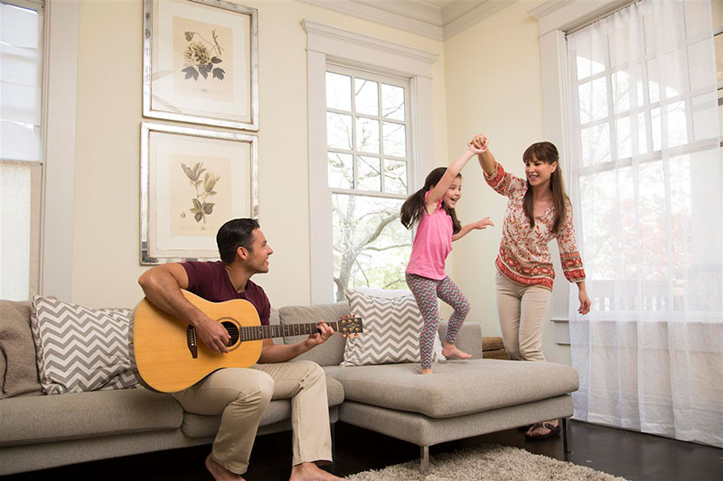 Padre tocando la guitarra mientras madre e hija bailan