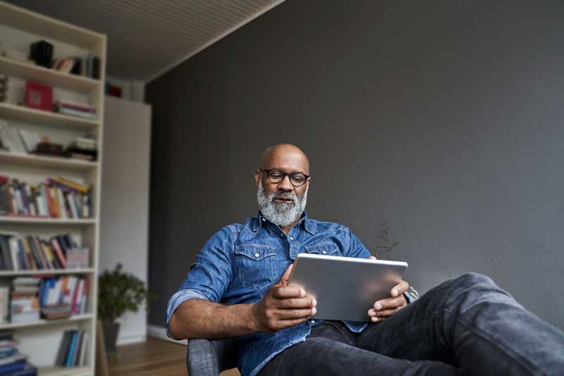 Un hombre relajado en su casa con su tableta