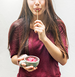 woman holding bowl and licking spoon
