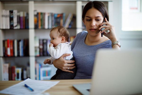 Una mamá ocupada trabajando con un teléfono celular y una computadora portátil que sostiene a su bebé Una mamá ocupada trabajando con un teléfono celular y una computadora portátil que sostiene a su bebé