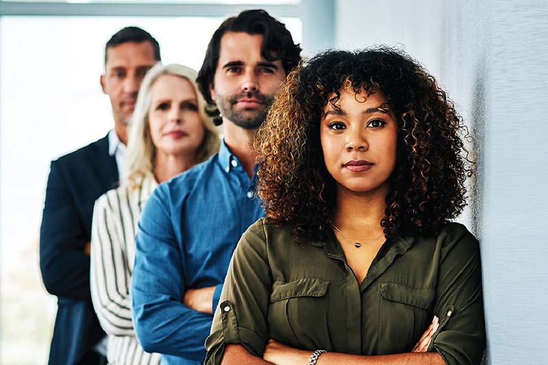 Diverse employees posing against a wall, arms folded