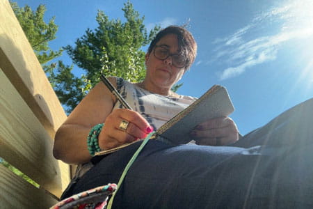 Go Red for Women Class of Survivors Tania Saiz outside writing in a journal