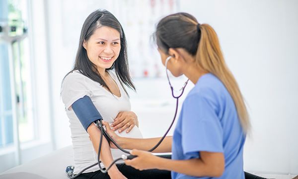 nurse checks pregnant woman's blood pressure nurse checks pregnant woman's blood pressure