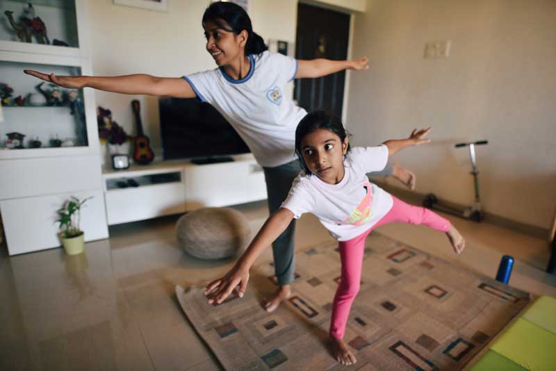 Mamá e hija haciendo una postura de equilibrio de yoga