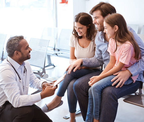 Smiling doctor talking with girl's father and mother