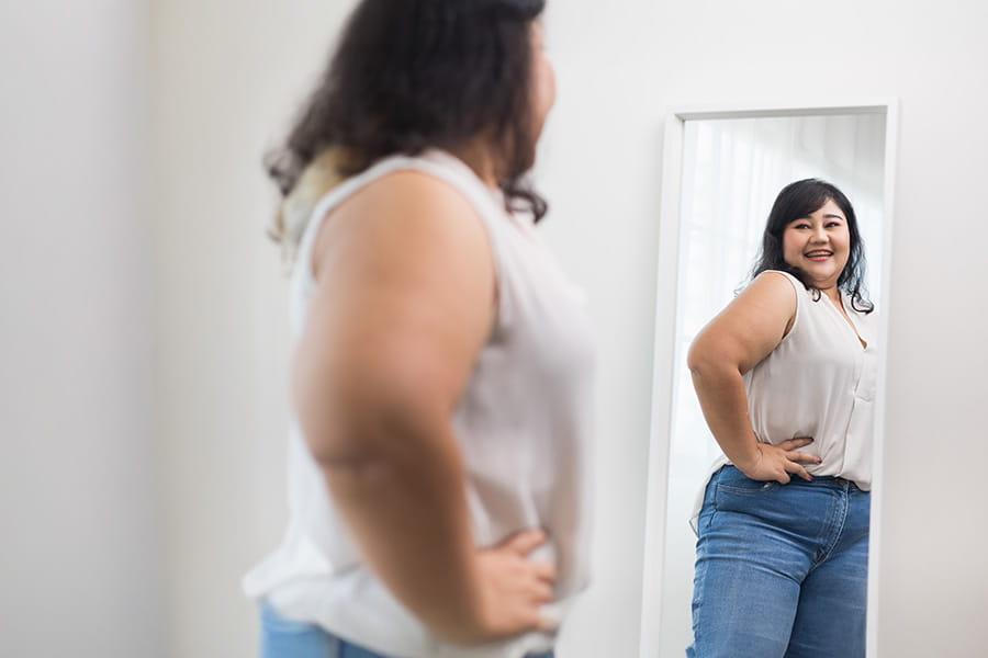 Girl trying clothes and looking in the mirror with a smile