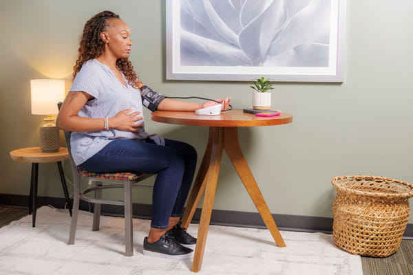 Class of Survivors member Anjellica Davis taking her blood pressure at a table.