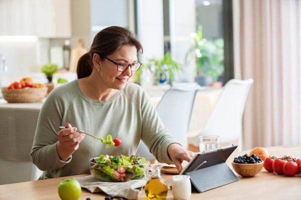 Woman scrolling her table and eating a salad