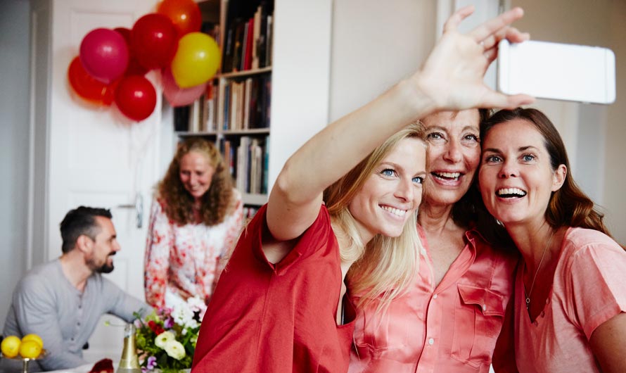 Mother and two daughters taking a selfie at a celebration