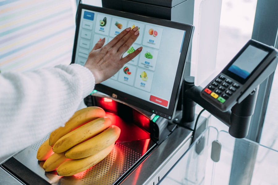 Woman weighing bananas at grocery store register