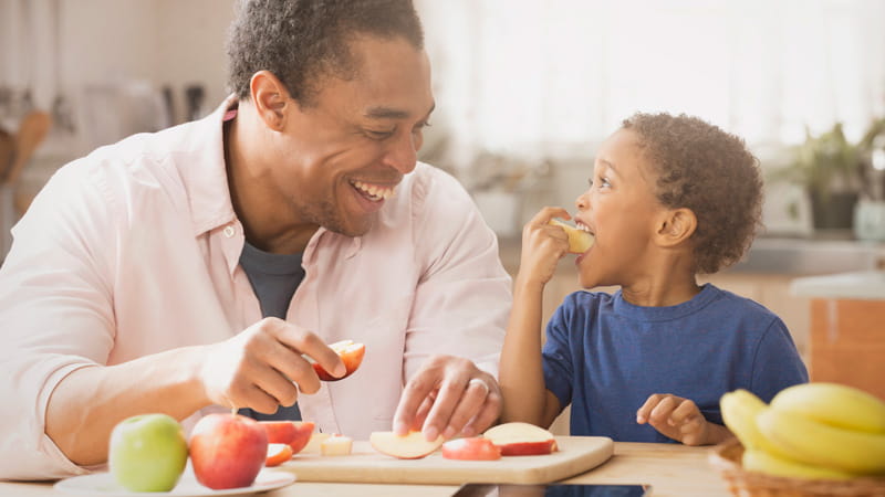 padre e hijo comiendo manzanas en la cocina