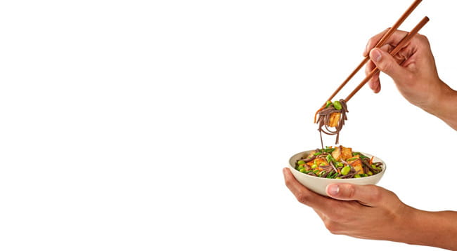 hand holding a bowl of stir fry