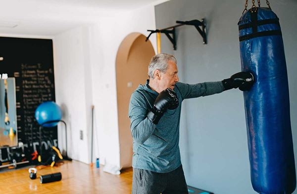 middle aged man punching a punching bag