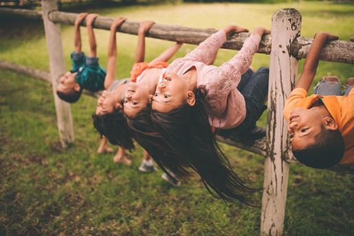 diverse mixed racial group of children on fence in park