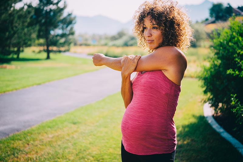 A pregnant woman exercising in a park.