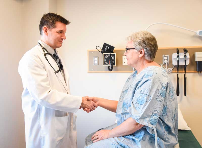 Paciente mujer que le da la mano al médico